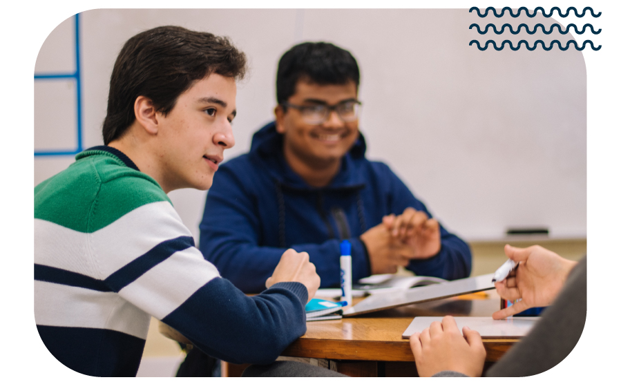 Two students in a classroom watching their teacher